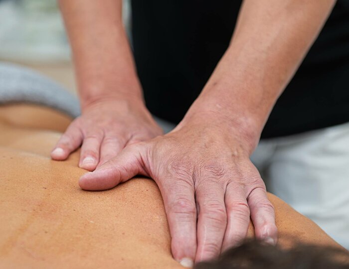 Classic Massage in the Kristall Spa A therapist massages the back of a reclining person with both hands in the Kristall Spa.