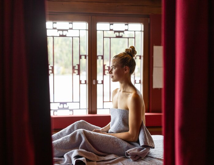 Thai massage in the Kristall Spa at Hotel Hochschober A woman sits wrapped in a towel on a massage table in the Kristall Spa.