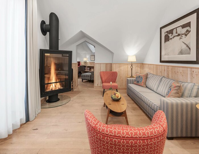 Suite living room with fireplace A cozy suite living room with a fireplace, sofa, armchair and light wood flooring.