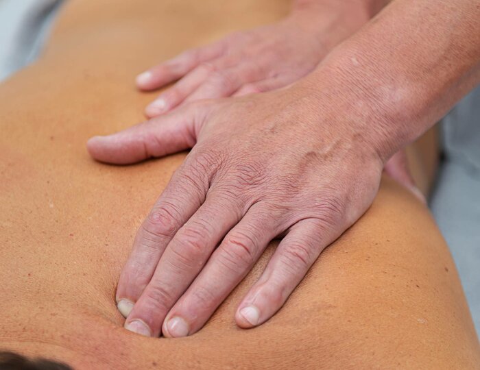Herbal oil massage at Kristall Spa Two hands massage the back of a lying person during a herbal oil massage at Kristall Spa.
