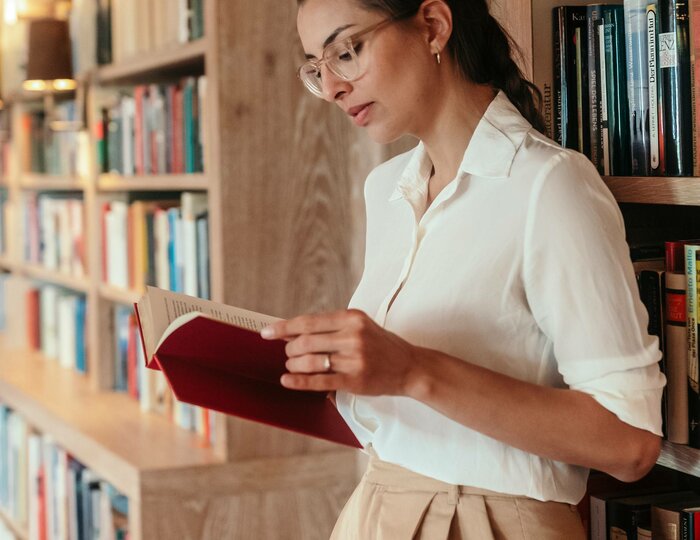 Hotel library with reader at Hotel Hochschober A woman reads in a wood-paneled hotel library while leaning against the bookshelves.