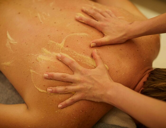Udvarthana massage in the Kristall Spa Hands massage a person's back with paste during an Udvarthana treatment in the spa.