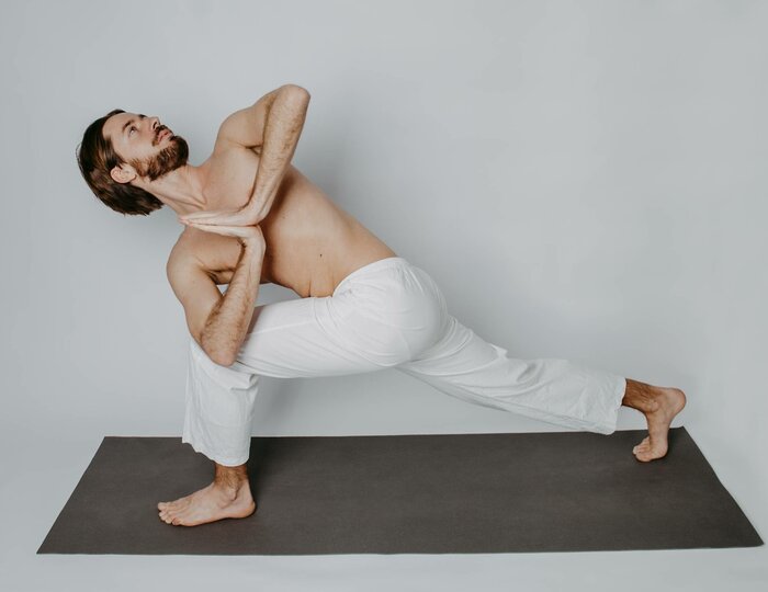 Yoga pose on mat at Hotel Hochschober A man holds an intense yoga pose on a yoga mat against a plain light background.
