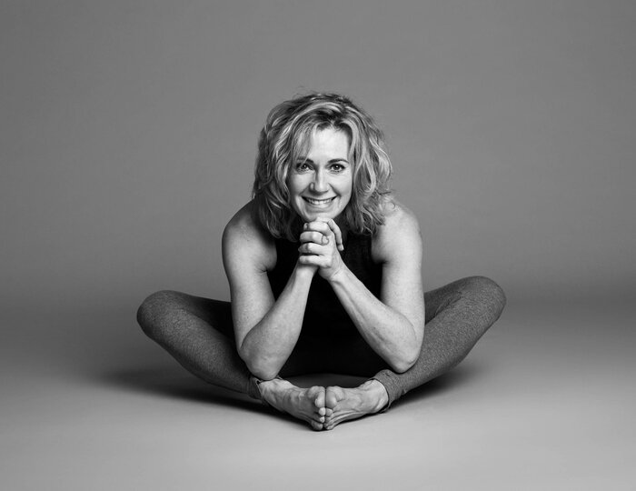Yoga pose at Hotel Hochschober A woman sits in a yoga pose on the floor and smiles at the camera.